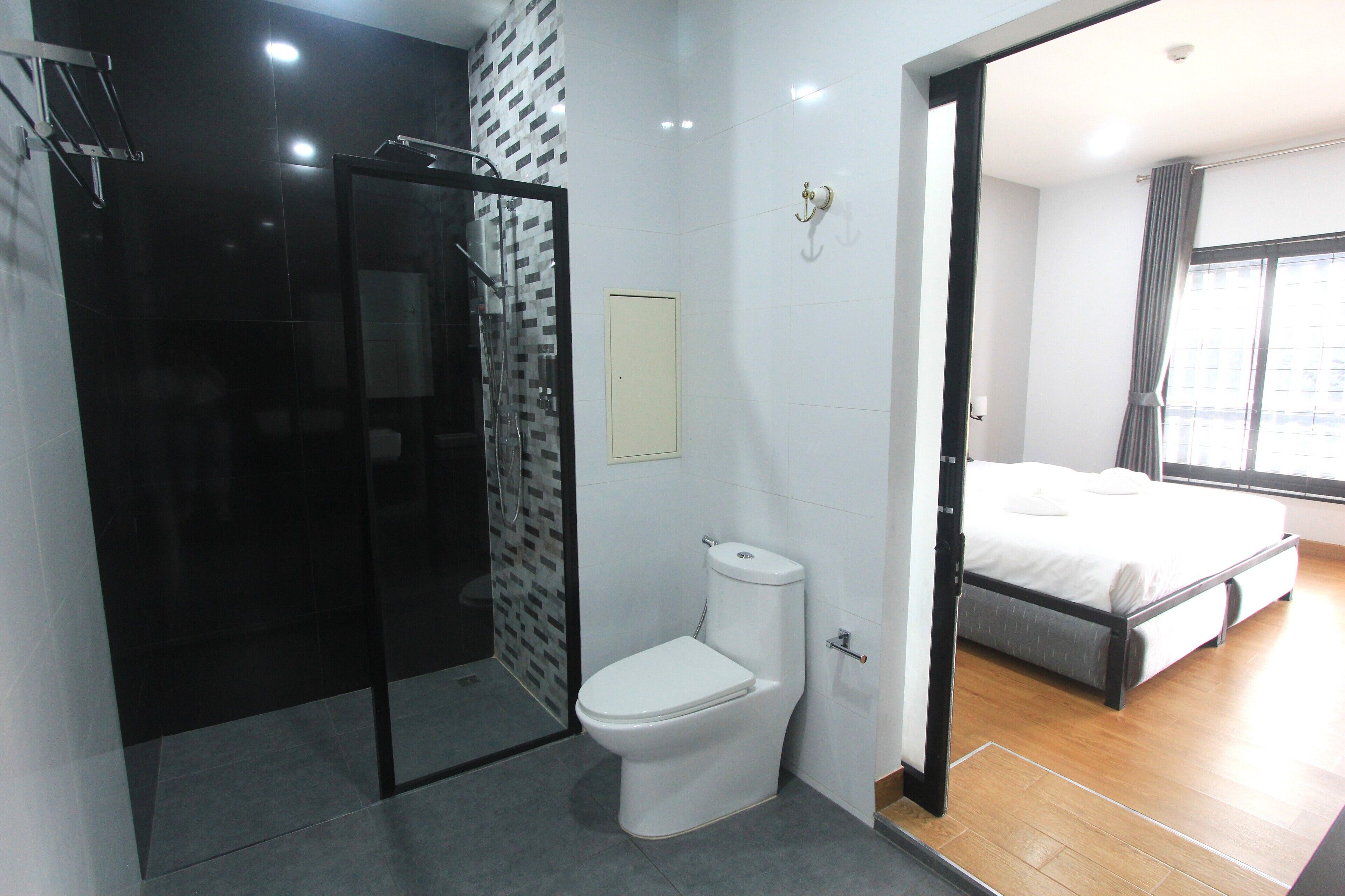A modern bathroom with a glass shower enclosure, a white toilet, and a wooden floor.