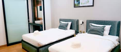 Two single beds with white linens and dark headboards, a small bedside table with a lamp, and a framed map on the wall.