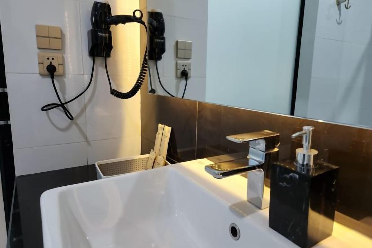 A modern bathroom with a white sink, a handheld hair dryer, and a mirror.