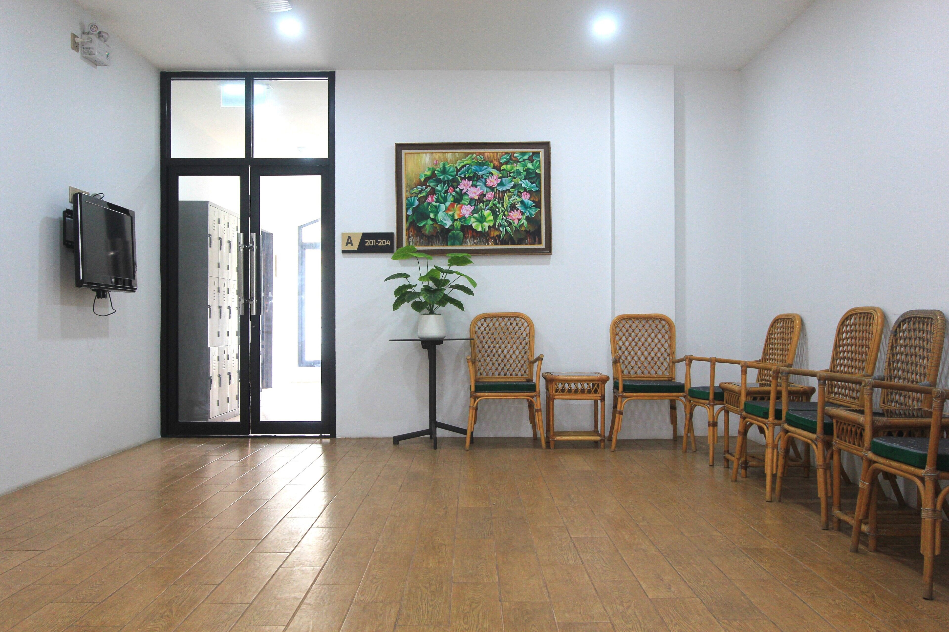 A room with a tiled floor, a television mounted on the wall, a door leading outside, and a framed painting above a table with chairs.