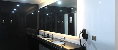 A modern bathroom with two sinks, a large mirror, and recessed lighting.