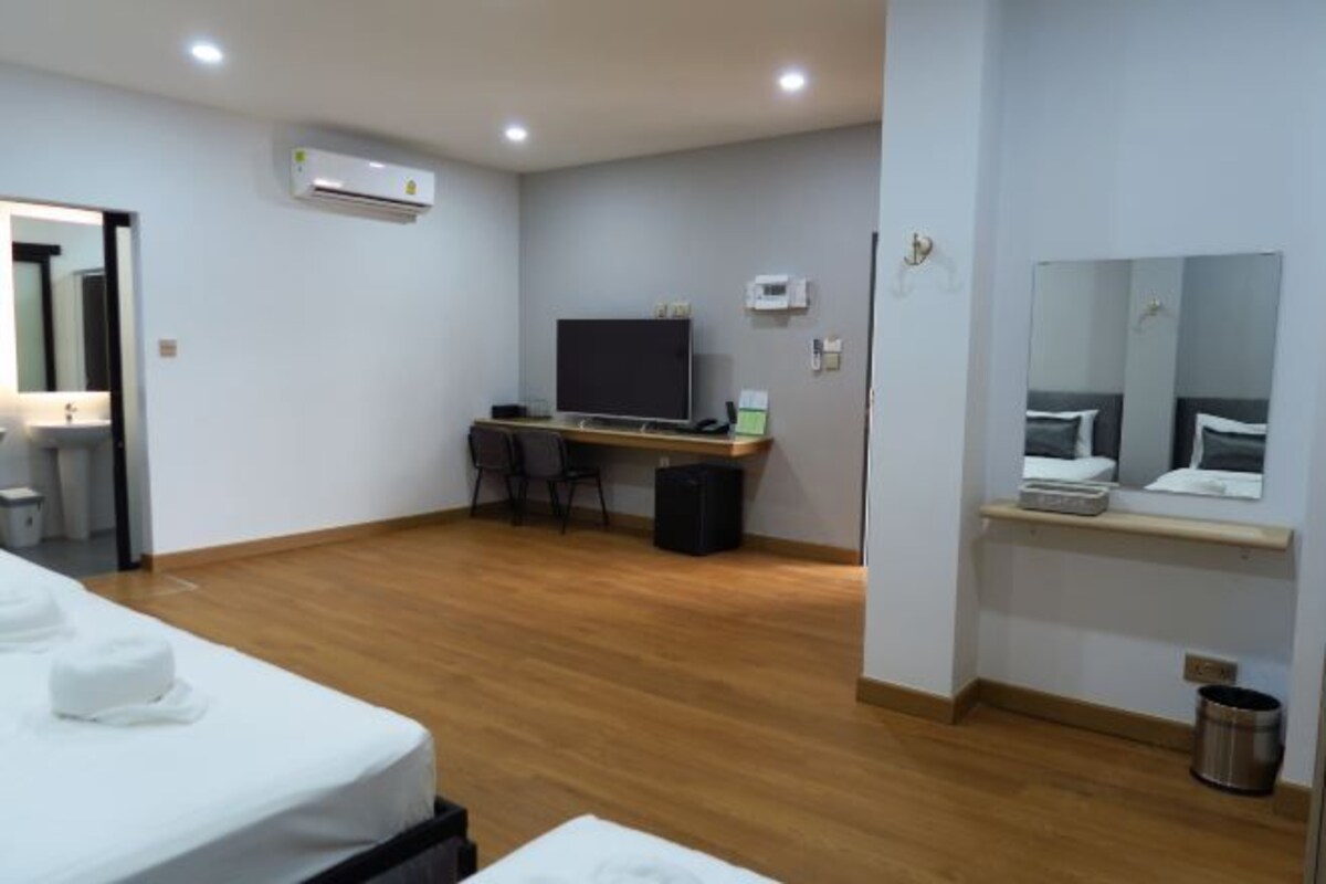 A hotel room with a bed, a desk with a computer, a TV, and a mirror.