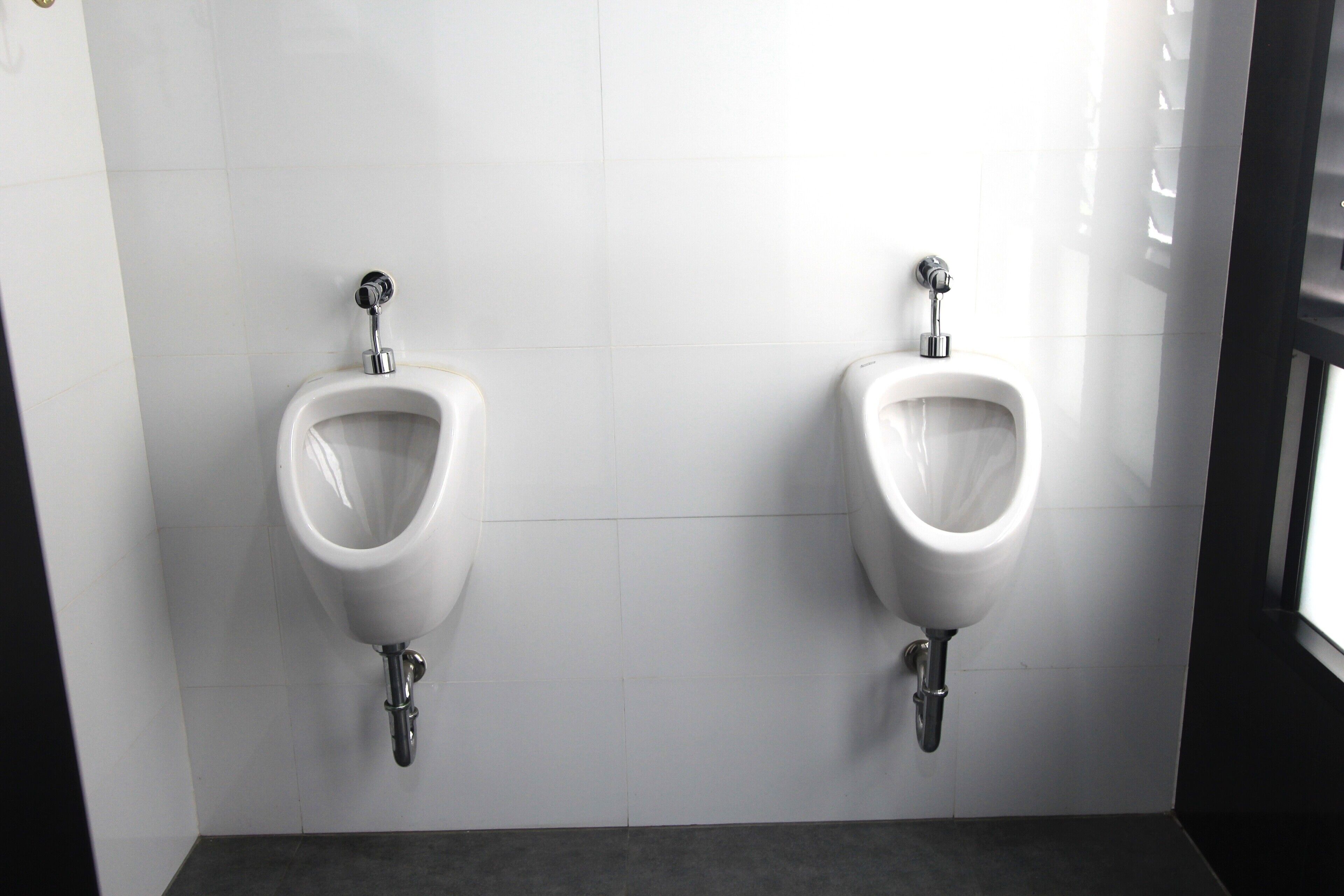 Dos orinales instalados en una pared de azulejos blancos en un baño.