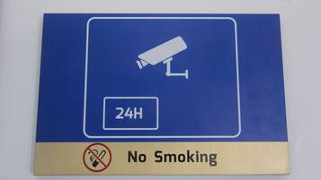Señal que indica prohibido fumar y vigilancia las 24 horas.