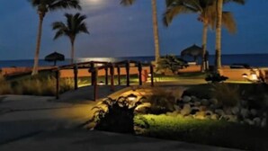 Une scène de plage nocturne avec des palmiers et une structure en bois.