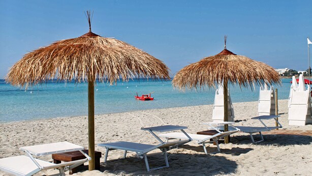 A beach with thatched umbrellas, lounge chairs, and a clear blue sea. - Porto Cesareo Air-conditioned Villa sleeps 12 “Torre Lapillo” (Porto cesareo)