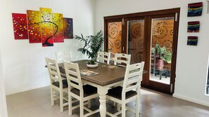 A dining area with a wooden table, white chairs, and a potted plant.