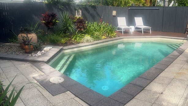 A rectangular swimming pool with clear water, surrounded by a tiled deck and potted plants. -  Murriyan A Tropical Villa (Port Douglas)