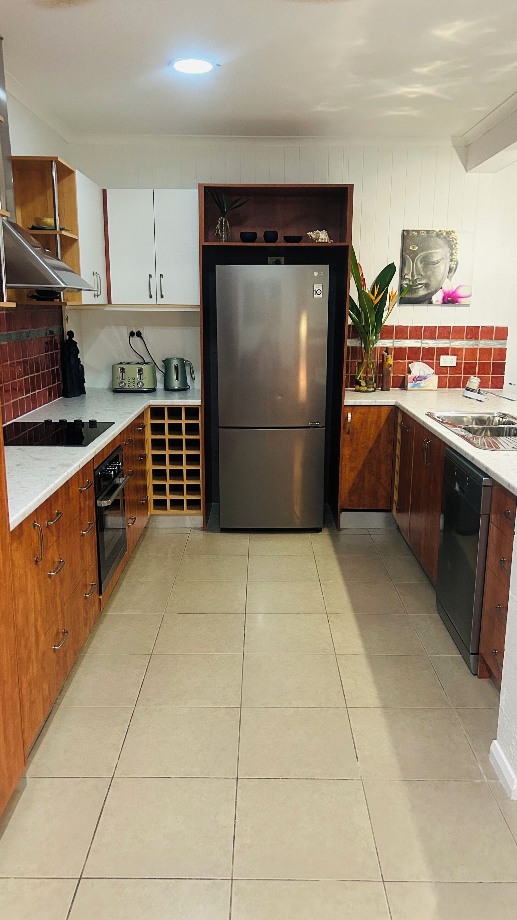 A kitchen with wooden cabinets, a stainless steel refrigerator, a sink, and a stove.