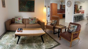 A living room with a sofa, armchairs, a coffee table, and a patterned rug. -  Murriyan A Tropical Villa (Port Douglas)