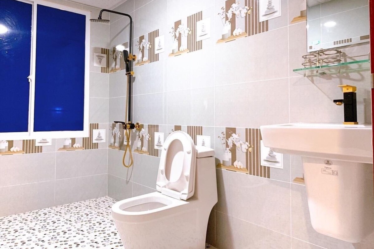 A modern bathroom with a toilet, shower, and sink.