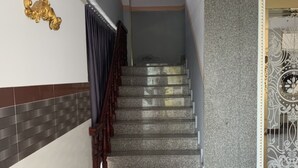Una escalera con barandilla, un muro con diseño y un detalle dorado decorativo.