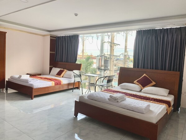 Habitación de hotel con dos camas, un balcón con mesa y sillas, y vista a la ciudad.