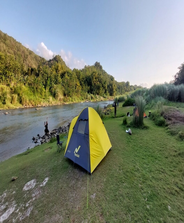 A tent set up near a river with a forested hillside in the background. - Potrobayan River Camp (Pundong)