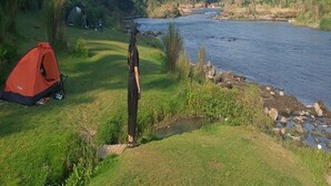 A campsite with tents and a river. - Potrobayan River Camp (Pundong)