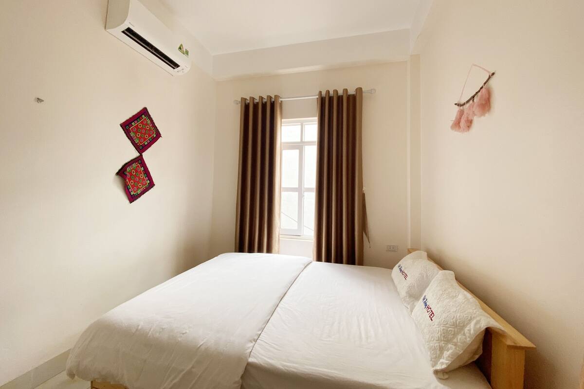Un dormitorio con cama, cortinas, aire acondicionado y un adorno en la pared.
