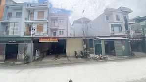 A hotel named Sunny Hotel with a closed shutter, a motorcycle parked in front, and a chicken on the road. - Sunny Bao Lac Homestay (Bao Lac)