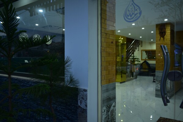 A modern hotel lobby with a glass entrance, a staircase, and a view of the outside. - Royal Continental Hotel Branch 2 (Mekhtar)