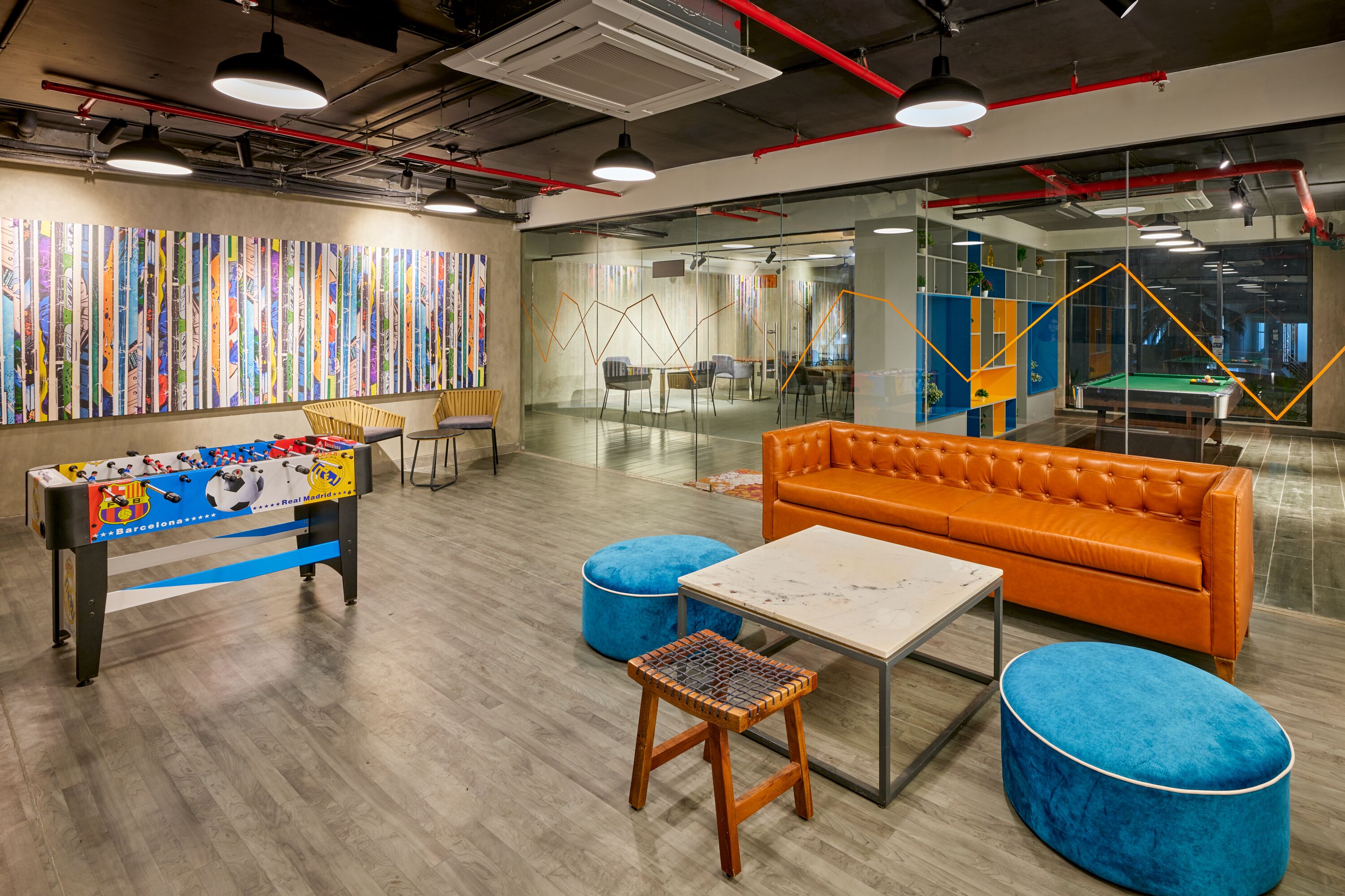 A modern office space with a foosball table, a sofa, and a ping pong table.
