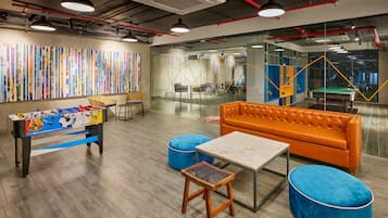 A modern office space with a foosball table, a sofa, and a ping pong table.