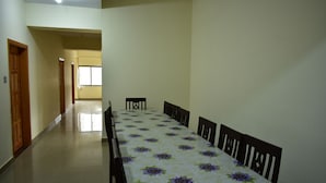 Un comedor con una mesa larga y sillas, una puerta de madera y un pasillo que conduce a otra habitación.