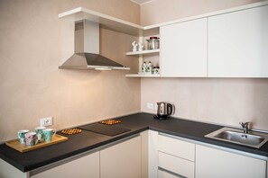 Een moderne keuken met een zwart aanrecht, een roestvrijstalen spoelbak en witte kasten.