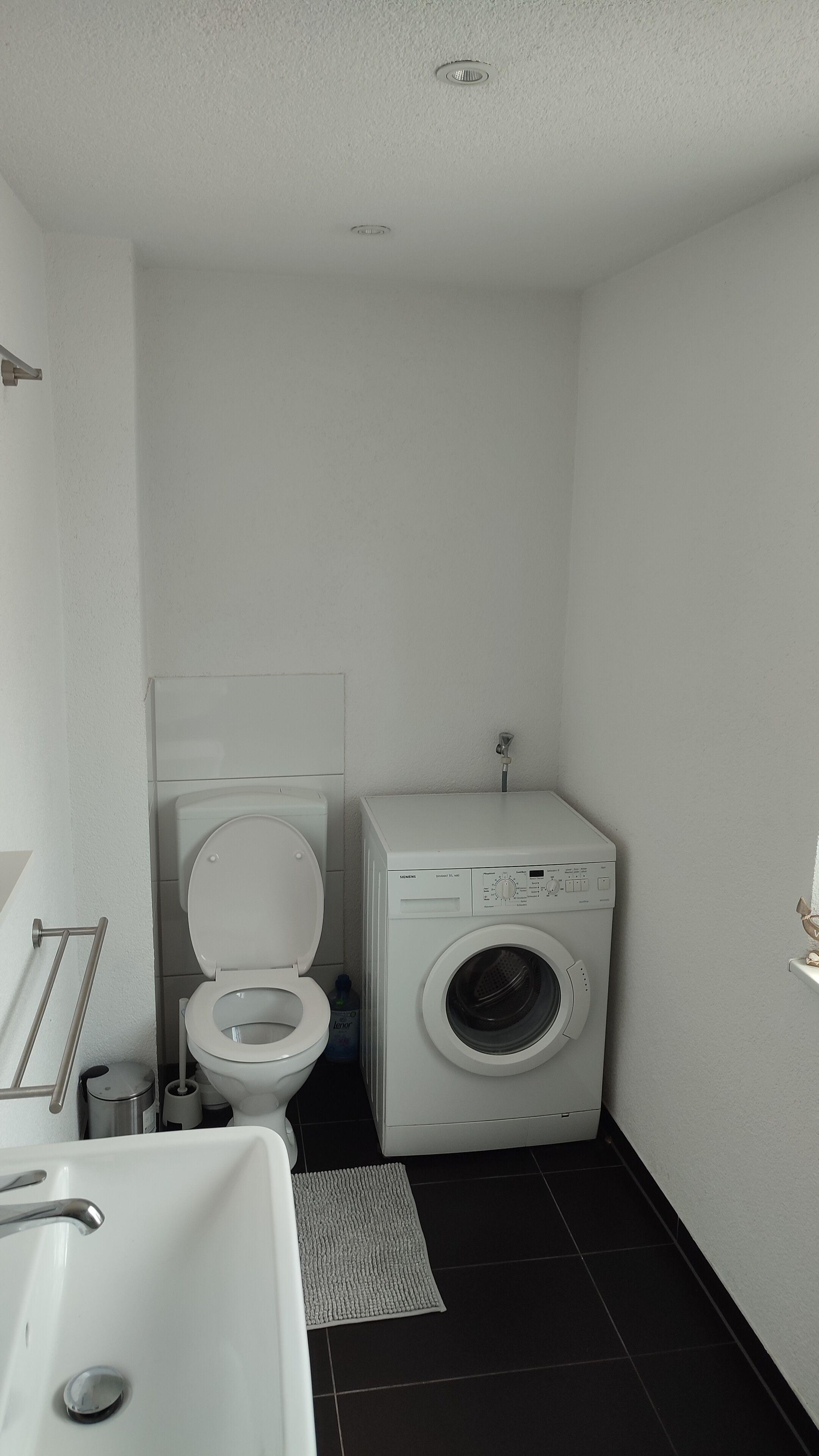 Un baño pequeño con inodoro, lavadora y lavamanos.