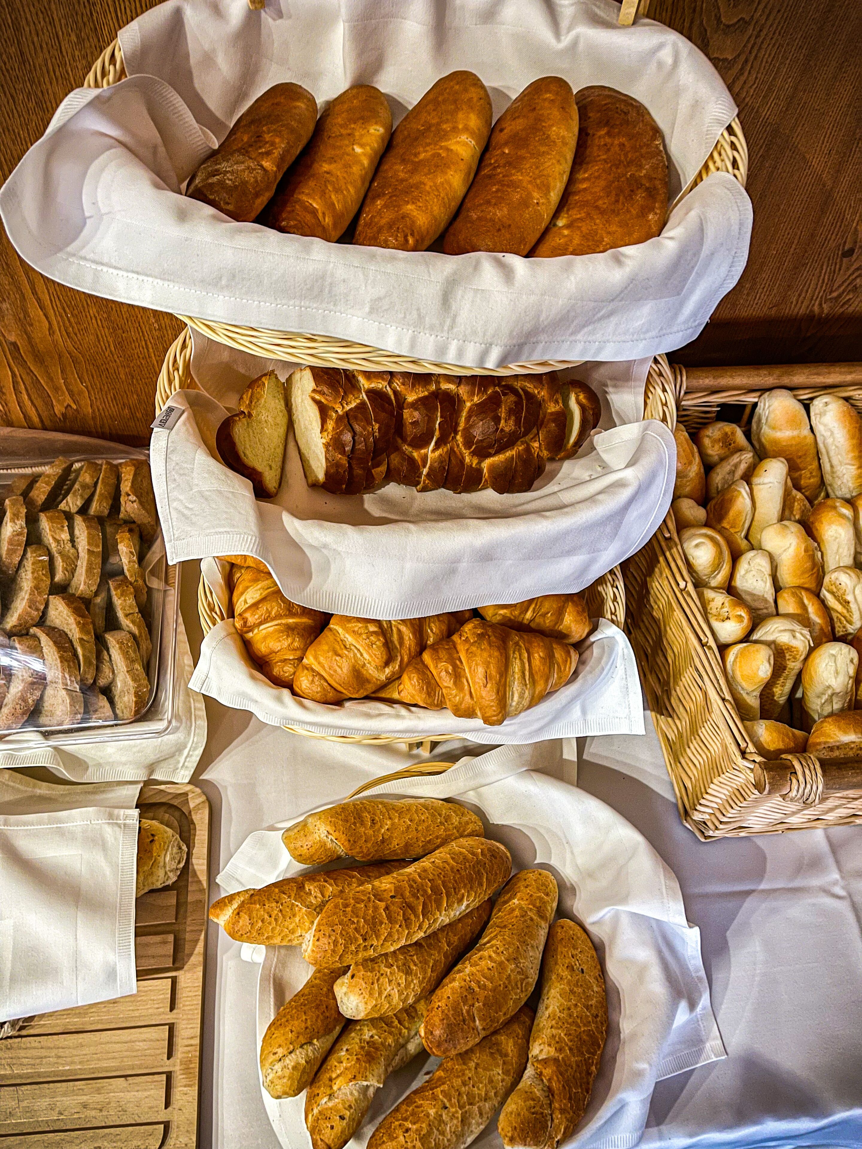 A variety of bread and pastries displayed in baskets and trays.