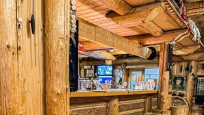A rustic interior with wooden walls, a bar area with stools, and a large wooden wheel. - Hotel Sova Ždiar (Zdiar)