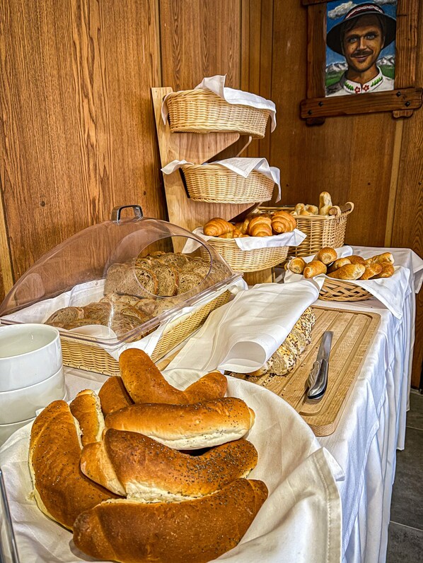 Un bufé de desayuno con panes, pasteles y un cuchillo sobre una mesa de madera.