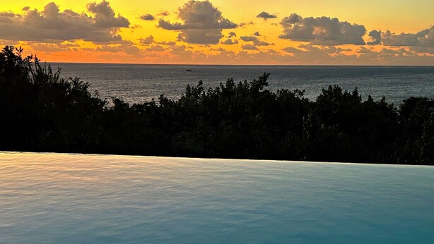A view of a pool with a clear sky and ocean in the background. - Villa Maya overlooking the bay, Jacuzzi, jetted bathtubs, pool table (Trou d'Eau Douce)