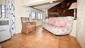 A living room with a sofa, a wicker chair, a heater, and a window with curtains. - Villa Maya overlooking the bay, Jacuzzi, jetted bathtubs, pool table (Trou d'Eau Douce)