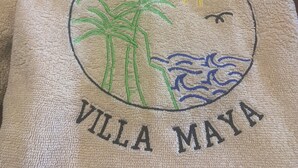 A towel with a circular design featuring palm trees, a sun, and waves, and the text "Villa Maya". - Villa Maya overlooking the bay, Jacuzzi, jetted bathtubs, pool table (Trou d'Eau Douce)