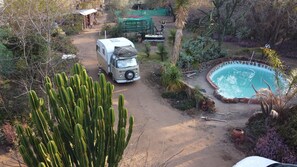 Una caravana estacionada cerca de una piscina rodeada de cactus y plantas del desierto.