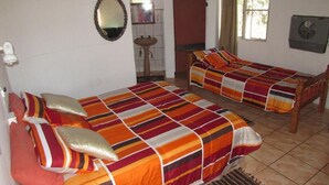 Une chambre avec deux lits, un miroir, un lavabo et une fenêtre avec des rideaux.