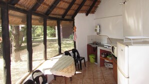 Un espace cuisine extérieur abrité, comprenant une table, des chaises et un réfrigérateur.