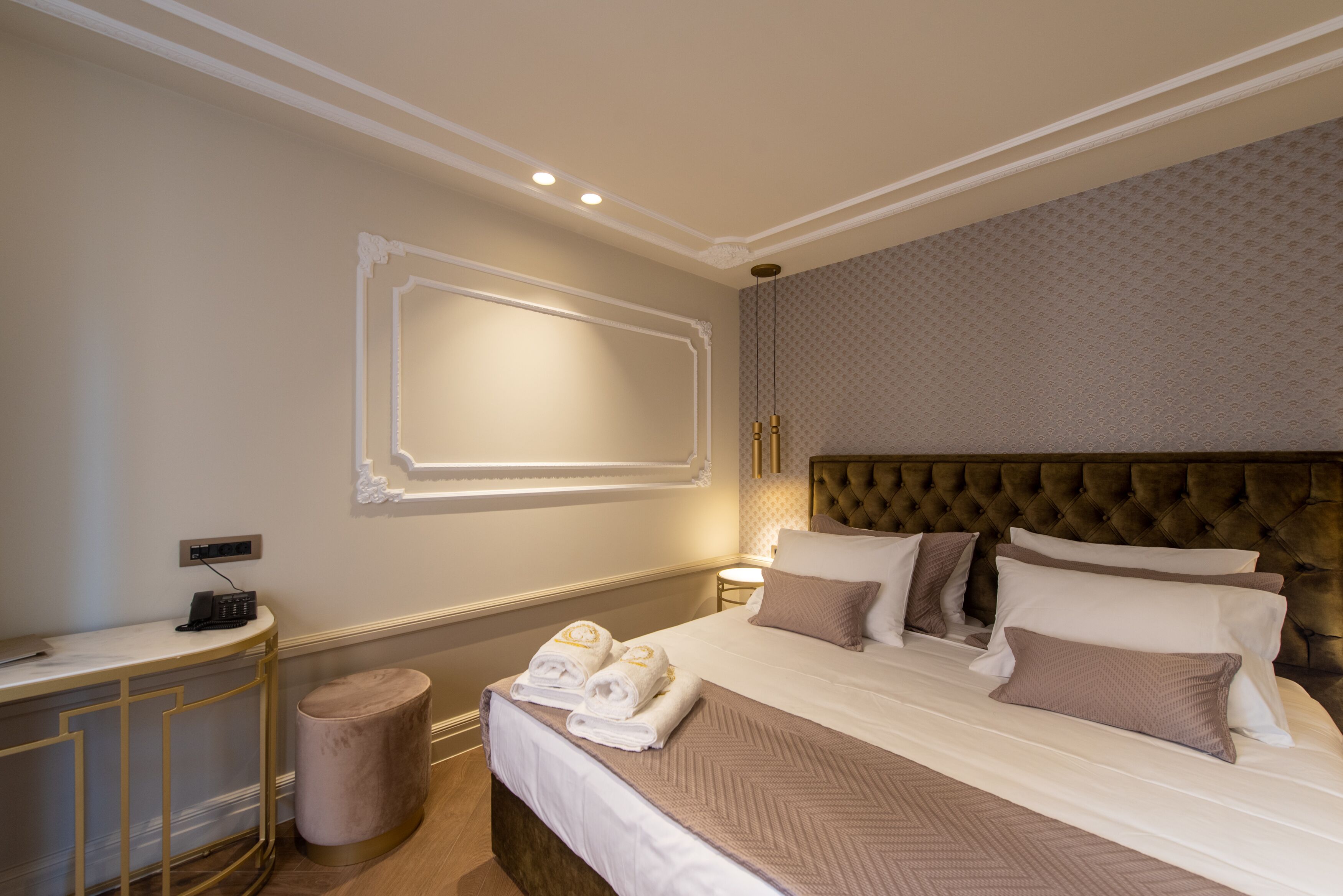 Une chambre d’hôtel avec un grand lit, une table de chevet avec une lampe, un téléviseur fixé au mur et une petite poubelle.