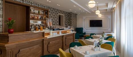Un restaurante con zona de bar, sillas verdes y amarillas, y un televisor montado en la pared.
