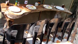A rustic wooden table with plates and cutlery, surrounded by black chairs. - Two Bedroomed Bush-tent on the Klaserie River, With Free Lion Hyena Sounds (Hoedspruit)