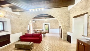 Un vaste espace de vie agrémenté d’un canapé rouge, d’un pouf et d’une table à manger placée à l’arrière-plan.