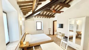 Une chambre à coucher comprenant un lit, un bureau, une chaise, un téléviseur et une armoire.