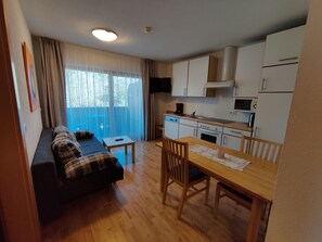 Un espace de vie compact comprenant un canapé, une table à manger et une kitchenette.