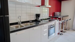 Une cuisine moderne avec des meubles blancs, un plan de travail noir, une machine à café et un four à micro-ondes.