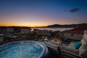 A rooftop terrace with a hot tub, seating area, and a view of the sea at sunset. - Apartment Alegria in Ciovo (Okrug)