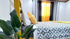 Una habitación de hotel con una cama, una planta en maceta, un control remoto y una bandeja amarilla.