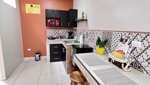 Una cocina compacta con microondas, fregadero y un pequeño comedor.
