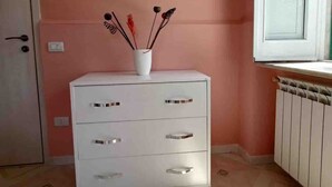 A room with a white dresser, a pink wall, and a window with blinds. - A Refuge Between Green And Blue (Tramonti)