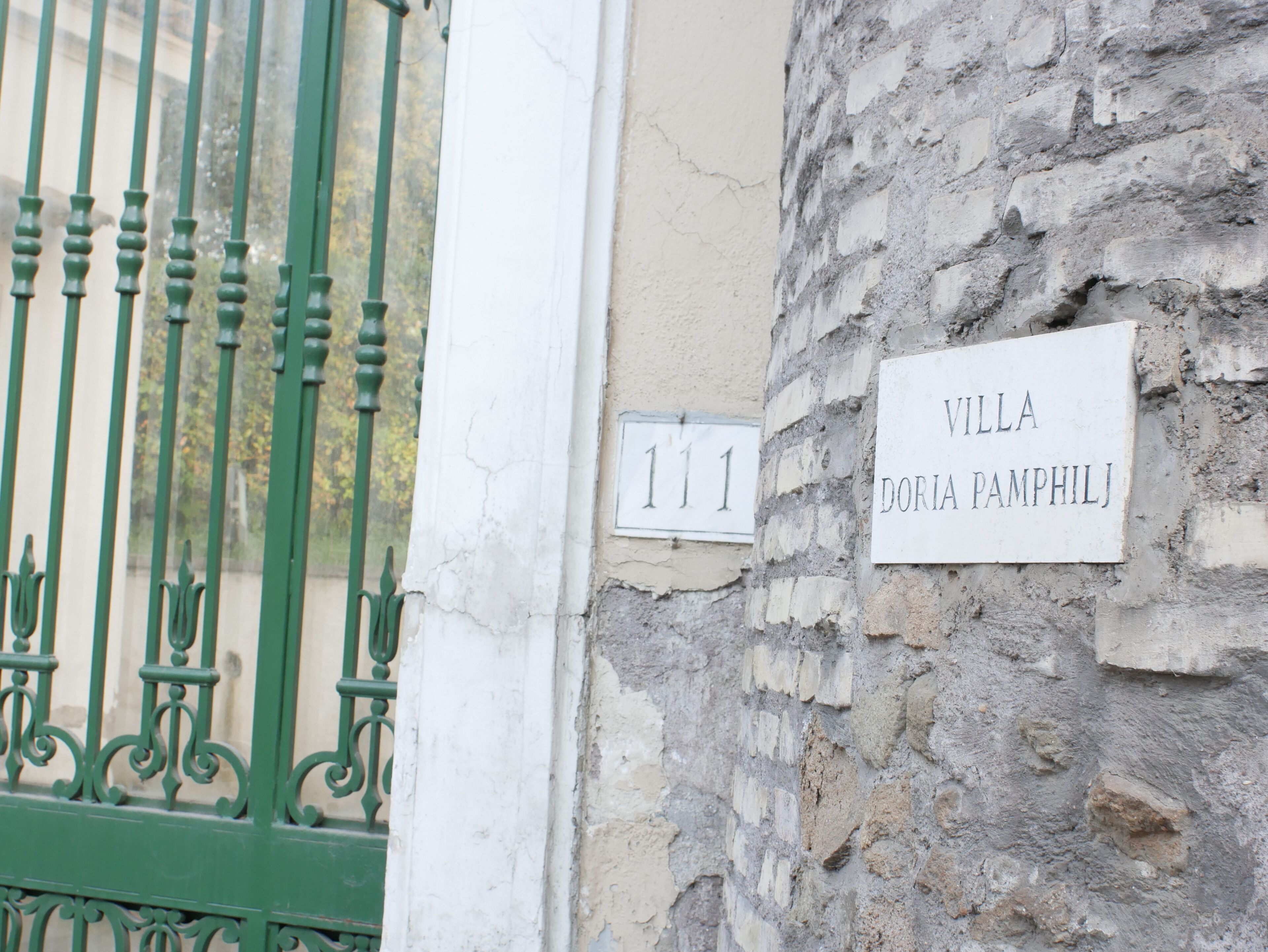 A stone wall with a sign reading 'VILLA DORIA PAMPHILJ' and a number '111' on a building.