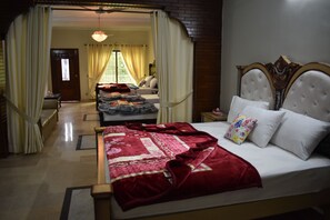 A hotel room with a large bed, a separate sitting area, and a view of the outdoors. - Neelum Guest House (Mekhtar)