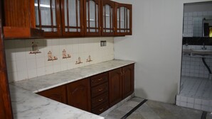 Una cucina con mobili in legno, un piano di lavoro in marmo e uno schienale piastrellato.